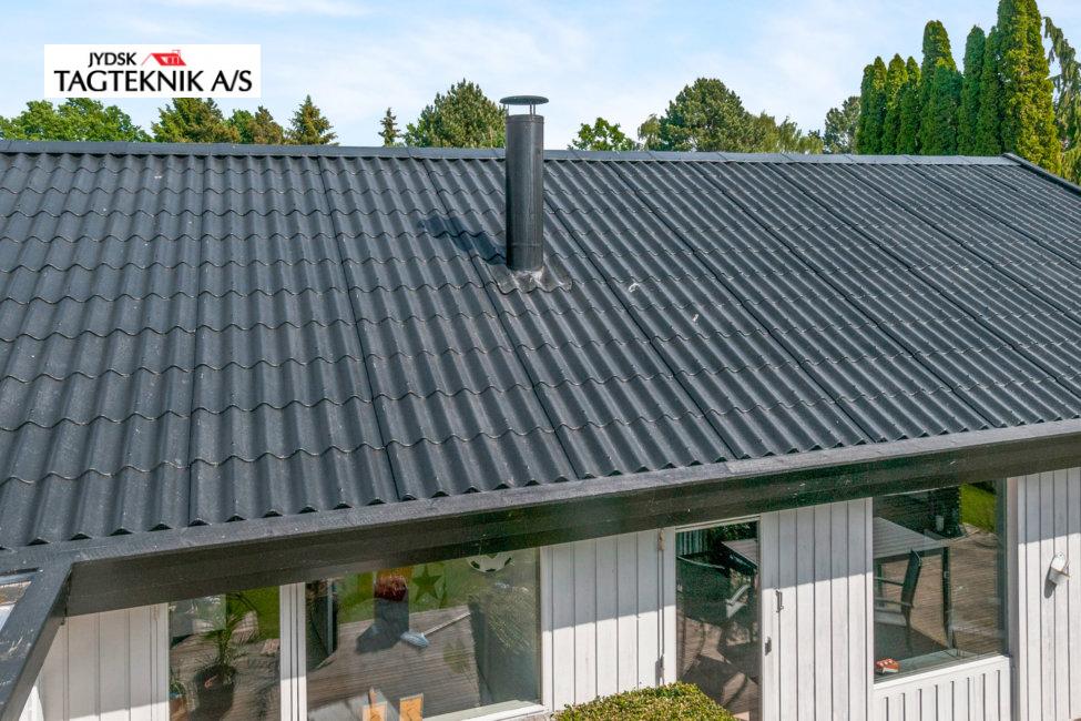 Sort bølgetag på et hus set oppefra med en sort skorsten.